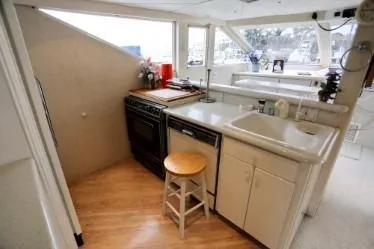 Scherzo Yacht Photos Pics Compact kitchen on a 1989 custom boat with stove, sink, and stool.