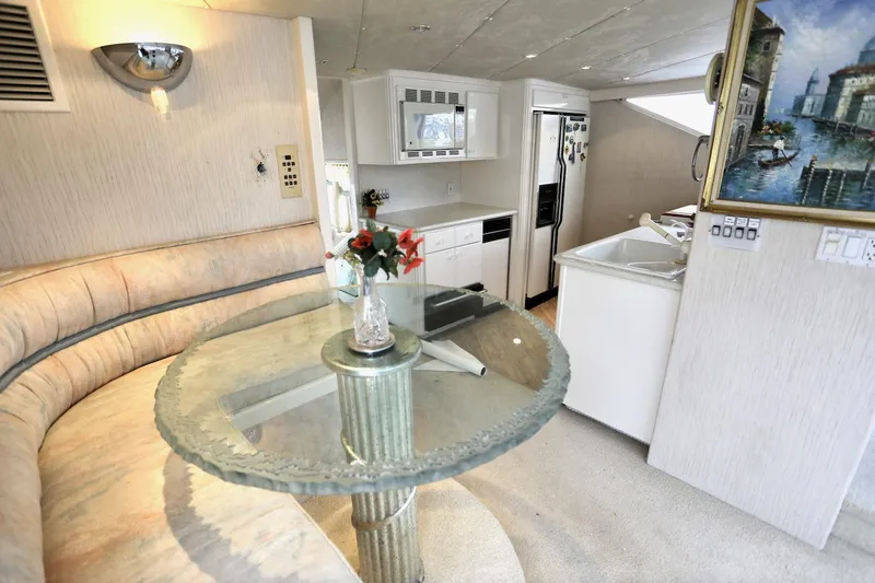Scherzo Yacht Photos Pics Luxurious yacht interior with glass table, curved seating, modern kitchen, and decorative painting, 1989 model.
