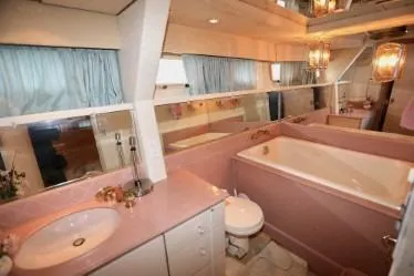 Scherzo Yacht Photos Pics Luxurious 1989 custom bathroom with pink fixtures, large bathtub, and elegant lighting.