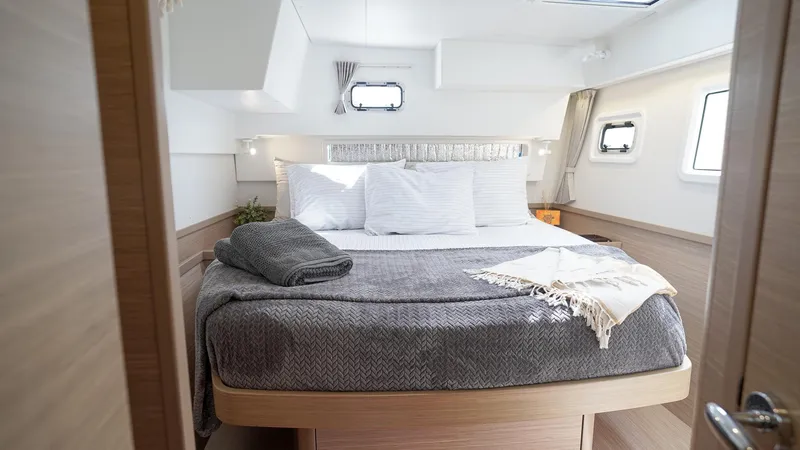Good Times And Tan Lines Yacht Photos Pics Luxurious cabin interior of 2023 Lagoon 42 catamaran with cozy bedding and modern design.