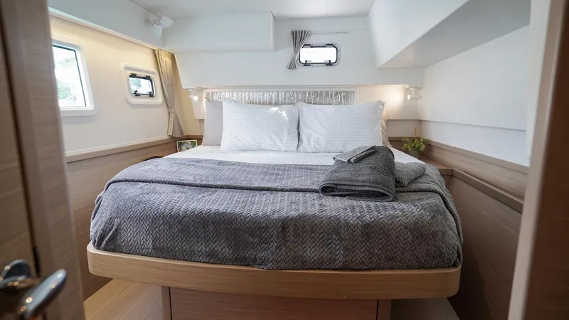 Good Times And Tan Lines Yacht Photos Pics Luxurious cabin interior of 2023 Lagoon 42 yacht with cozy bed and modern design.