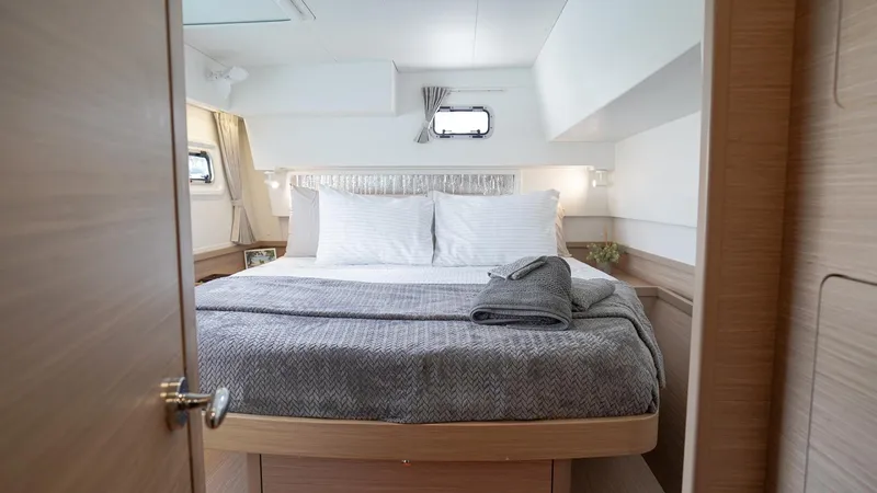 Good Times And Tan Lines Yacht Photos Pics Luxurious cabin interior of 2023 Lagoon 42 catamaran with cozy bed and modern design.