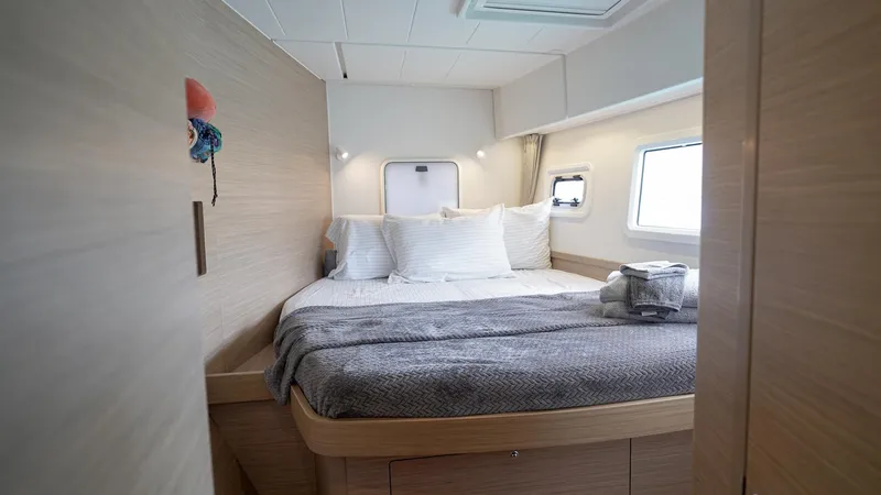 Good Times And Tan Lines Yacht Photos Pics 2023 Lagoon 42 yacht cabin with cozy bed, modern design, and natural light.