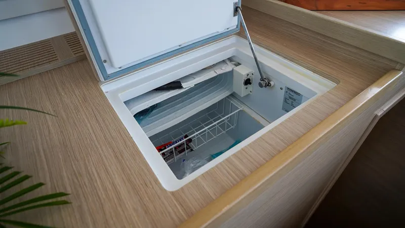 Good Times And Tan Lines Yacht Photos Pics Open freezer compartment on 2023 Lagoon 42 yacht, featuring wooden countertop and interior storage.