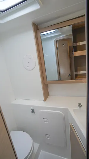 Good Times And Tan Lines Yacht Photos Pics 2023 Lagoon 42 yacht bathroom with mirror, storage, and modern fixtures.