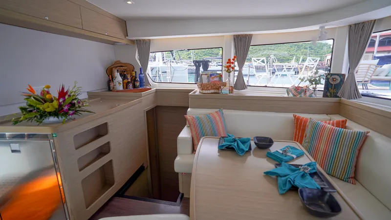 Good Times And Tan Lines Yacht Photos Pics Luxurious interior of 2023 Lagoon 42 yacht with elegant dining area and vibrant decor.