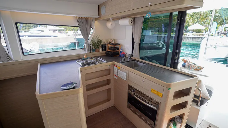 Good Times And Tan Lines Yacht Photos Pics Modern kitchen interior of 2023 Lagoon 42 catamaran with sleek design and marina view.
