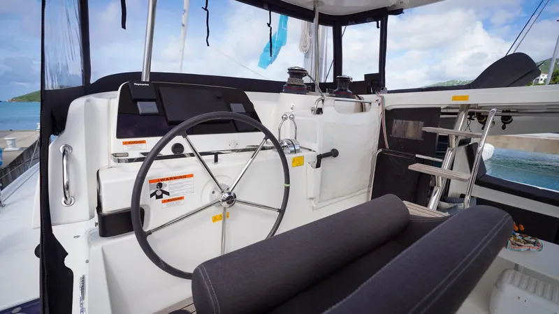 Good Times And Tan Lines Yacht Photos Pics Helm of 2023 Lagoon 42 catamaran with steering wheel and navigation controls.