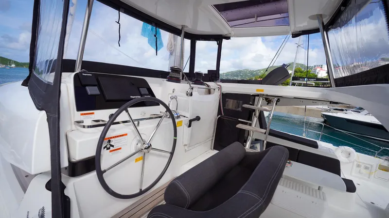 Good Times And Tan Lines Yacht Photos Pics 2023 Lagoon 42 yacht cockpit with steering wheel and navigation equipment.