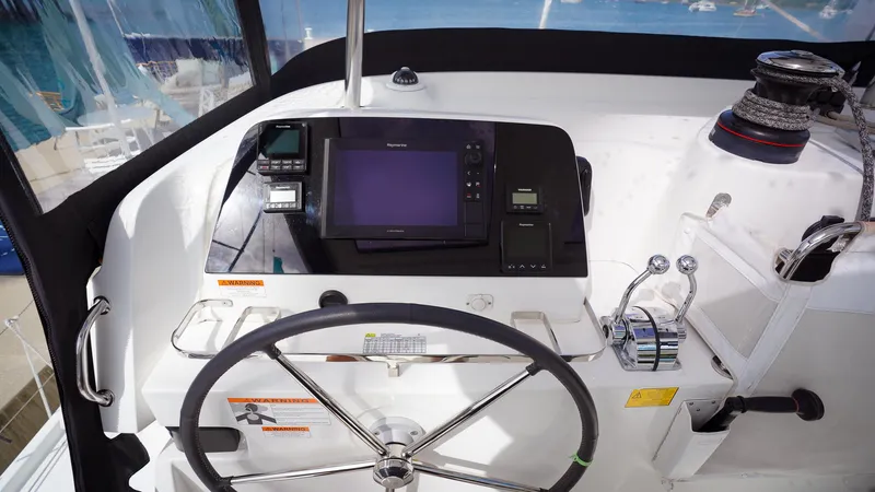 Good Times And Tan Lines Yacht Photos Pics 2023 Lagoon 42 yacht helm with navigation controls and steering wheel.