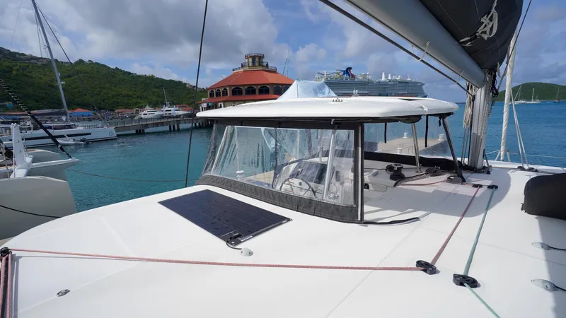Good Times And Tan Lines Yacht Photos Pics 2023 Lagoon 42 catamaran docked in a scenic marina with cruise ship in background.