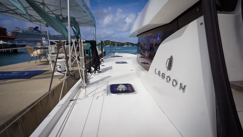 Good Times And Tan Lines Yacht Photos Pics 2023 Lagoon 42 catamaran docked at marina, showcasing sleek design and branding.