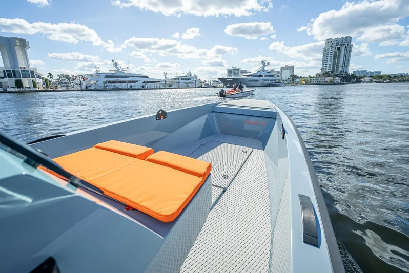  Yacht Photos Pics 2024 Goldfish 28 Tender boat on water with orange cushions, cityscape in background.