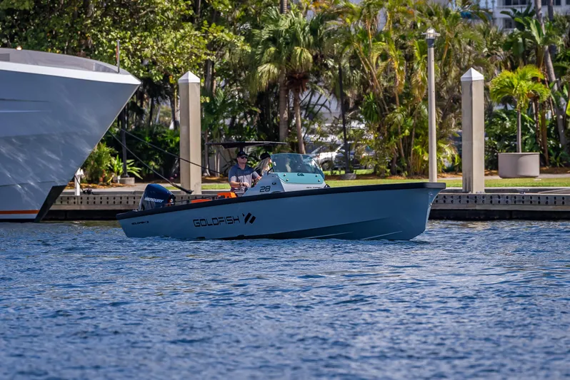  Yacht Photos Pics 2024 Goldfish 28 Tender boat cruising near a marina with lush greenery.