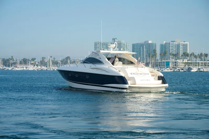 Distraction Yacht Photos Pics Sunseeker Camargue 50 yacht cruising in marina, 2000 model, cityscape background.