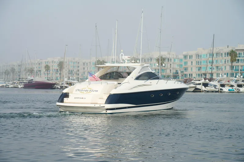 Distraction Yacht Photos Pics Sunseeker Camargue 50 yacht from 2000 cruising in a marina with modern buildings.