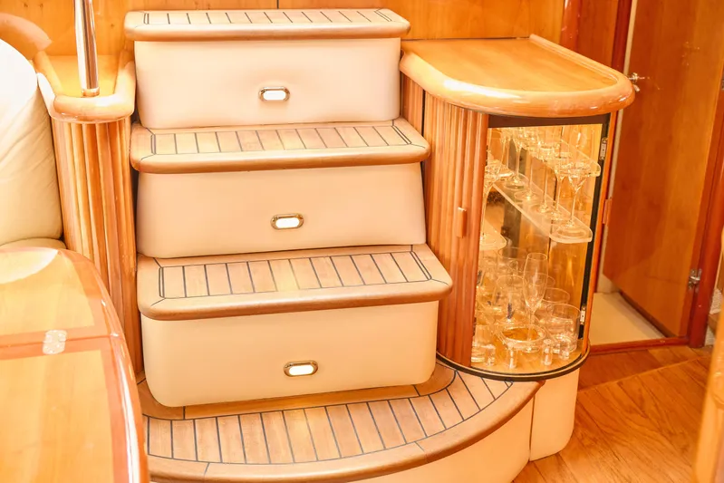 Distraction Yacht Photos Pics Luxurious interior of 2000 Sunseeker Camargue 50 yacht with elegant wooden stairs and glass cabinet.