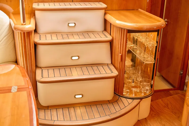 Distraction Yacht Photos Pics Luxurious interior of 2000 Sunseeker Camargue 50 yacht with elegant wooden steps and glass cabinet.