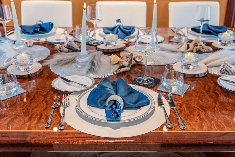 Just Enough Yacht Photos Pics Elegant dining setup on Ares Custom Marine 2012 yacht, featuring blue napkins and candles.