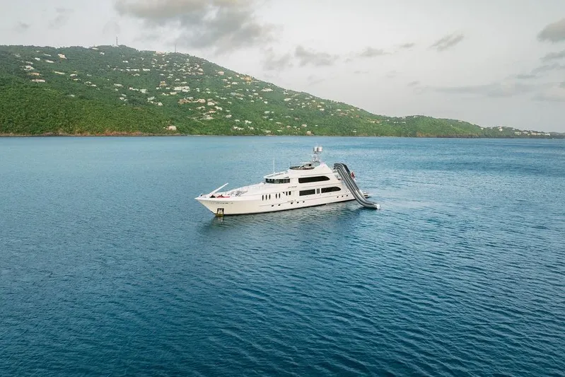 Just Enough Yacht Photos Pics Luxurious 2012 Ares Custom Marine 141 yacht with slide, anchored near lush green island.