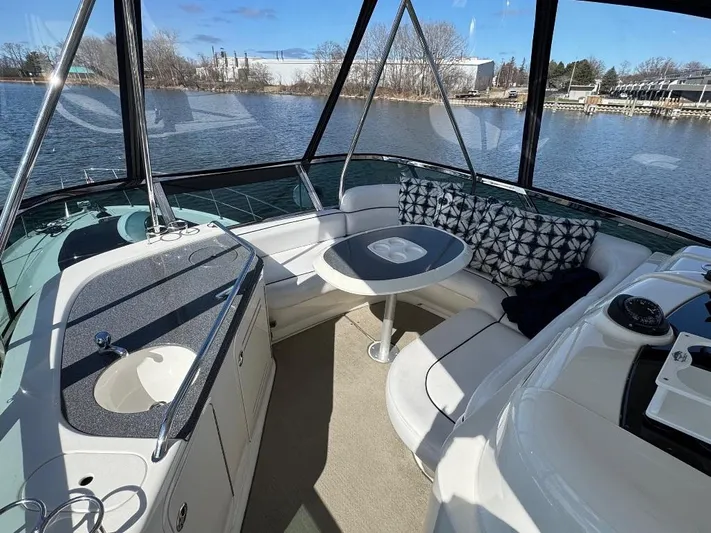  Yacht Photos Pics 2005 Sea Ray 500 Sedan Bridge interior with seating and table, overlooking a serene waterfront.