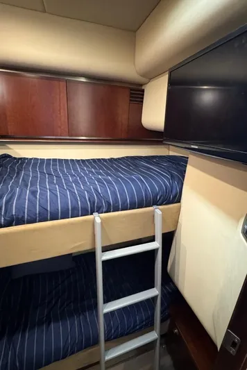  Yacht Photos Pics Bunk beds in 2005 Sea Ray 500 Sedan Bridge yacht cabin with striped bedding and wooden accents.