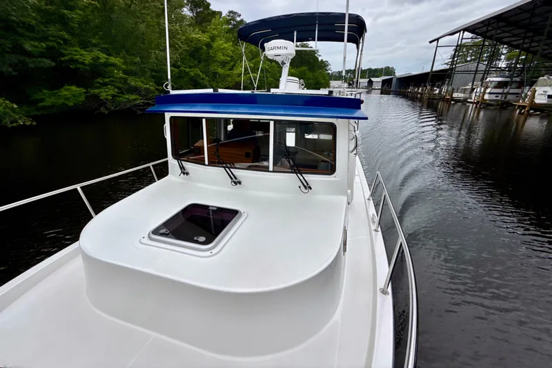 Blue Wander Yacht Photos Pics 2023 Nordic Tug 34 cruising on a calm river with lush greenery.