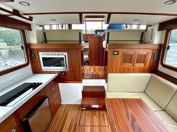 Blue Wander Yacht Photos Pics Interior of 2023 Nordic Tug 34, featuring wood finishes, seating, and kitchen area.