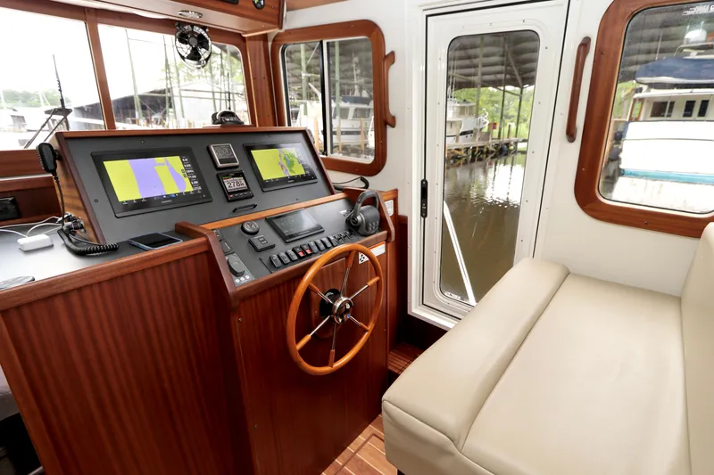 Blue Wander Yacht Photos Pics 2023 Nordic Tug 34 Tug helm with navigation screens and wooden steering wheel.