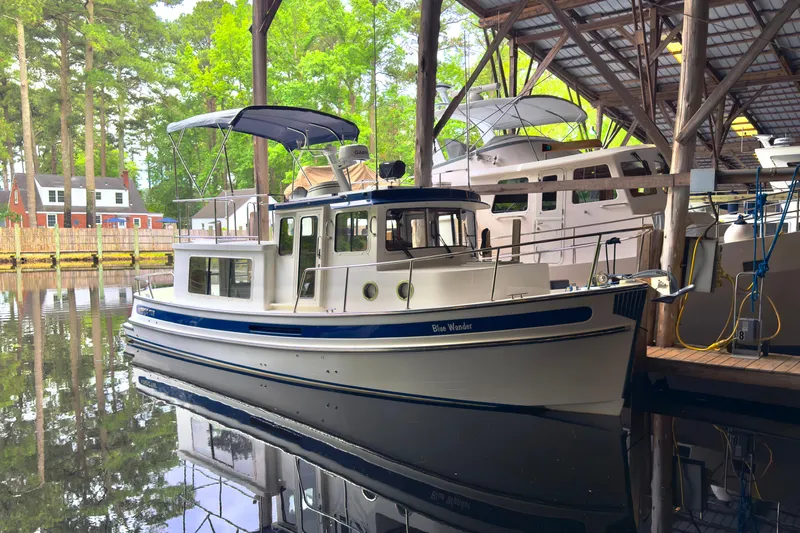 Blue Wander Yacht Photos Pics 2023 Nordic Tug 34 docked in a serene marina setting.