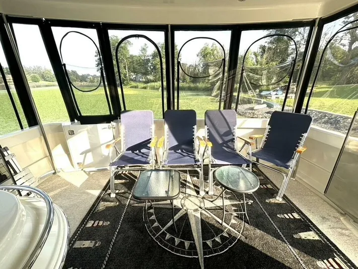  Yacht Photos Pics Interior of 2004 Carver 466 Motor Yacht with chairs and glass tables, surrounded by windows.