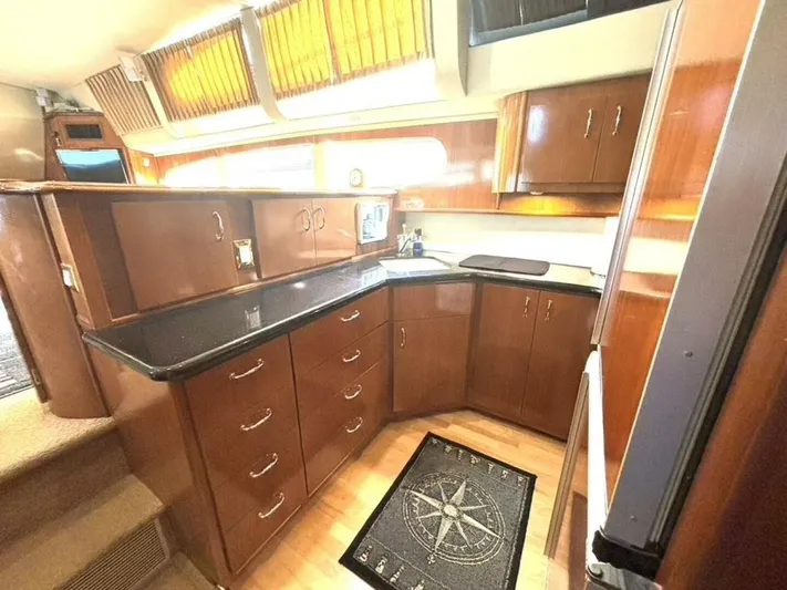  Yacht Photos Pics Luxurious kitchen interior of 2004 Carver 466 Motor Yacht with wood cabinetry and black countertops.