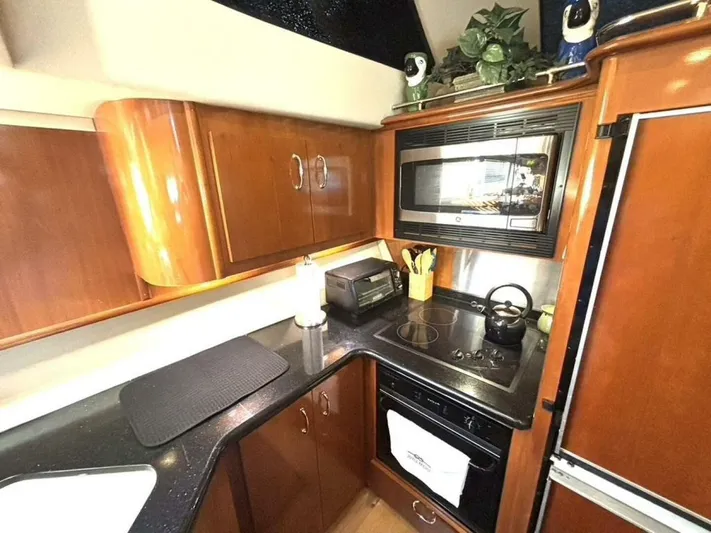  Yacht Photos Pics 2004 Carver 466 Motor Yacht kitchen with wood cabinets, microwave, and stovetop.