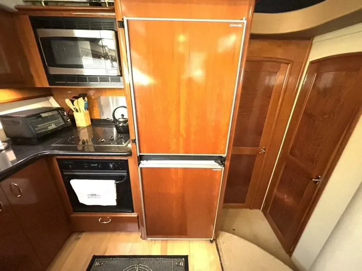  Yacht Photos Pics 2004 Carver 466 Motor Yacht kitchen with wooden cabinetry, refrigerator, and appliances.