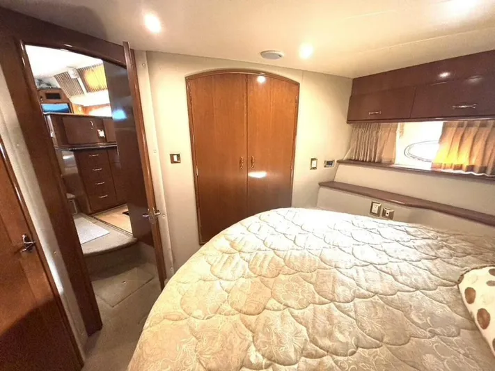  Yacht Photos Pics Interior of 2004 Carver 466 Motor Yacht bedroom with cozy bed and wooden cabinetry.