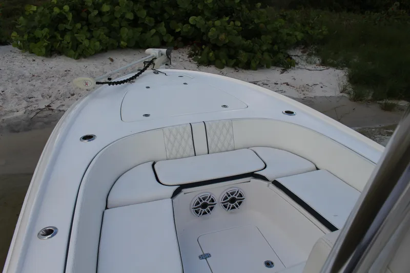  Yacht Photos Pics 2023 Contender 26 Bay boat with white seating and speakers, docked on sandy shore.