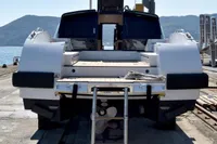 2023 Custom Limo Tender yacht on dock with ladder, rear view, mountainous background.