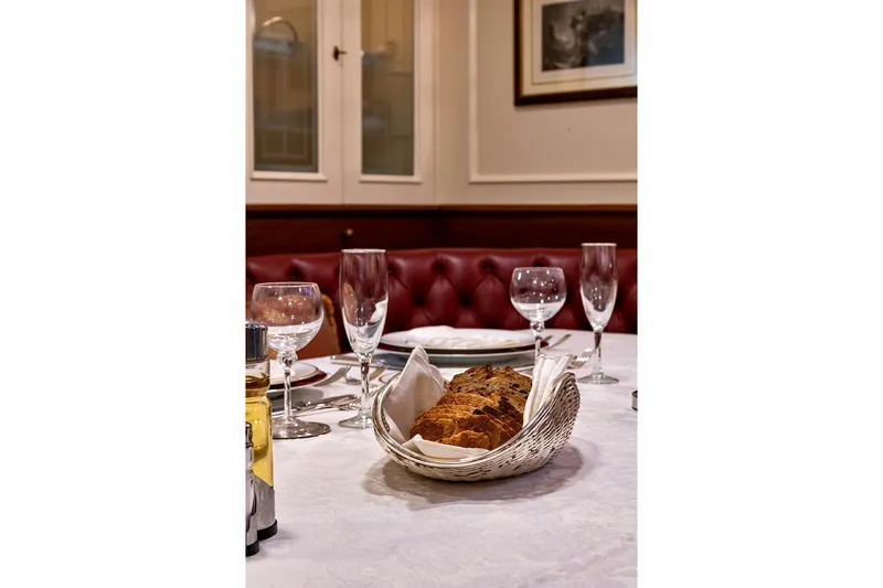 Invader Yacht Photos Pics Elegant dining setup with bread basket, glassware, and white tablecloth on a Gaff Schooner, 1905.