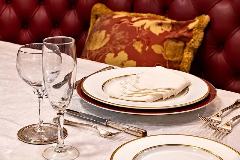 Invader Yacht Photos Pics Elegant table setting with fine china, glassware, and a decorative cushion in a luxurious dining area.