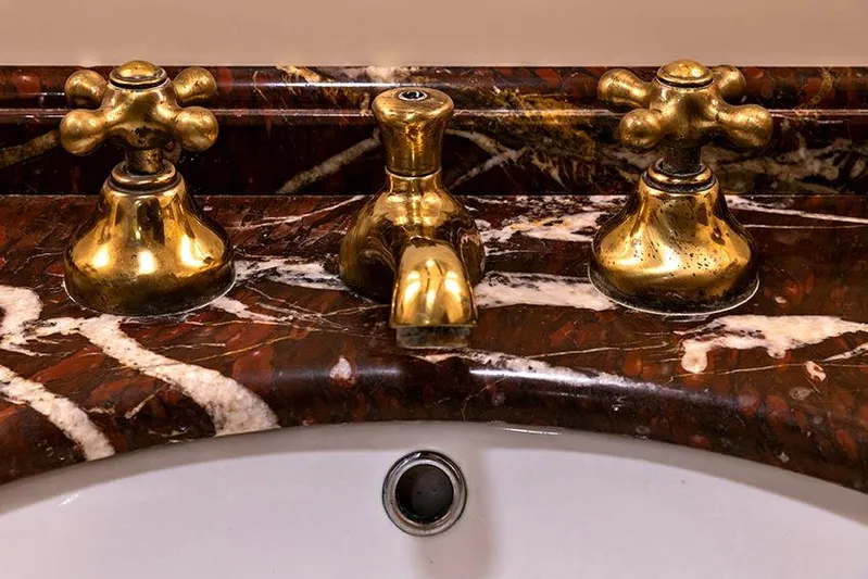 Invader Yacht Photos Pics Vintage brass faucet set on a luxurious marble countertop.