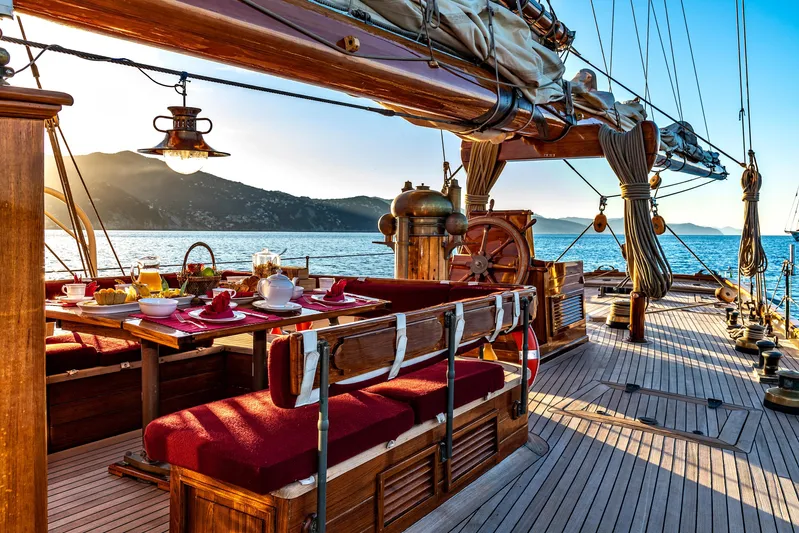 Invader Yacht Photos Pics Luxurious 1905 Gaff Schooner deck with elegant dining setup at sunset.