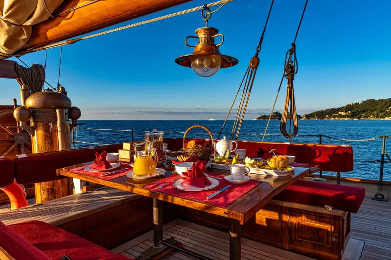 Invader Yacht Photos Pics Luxurious breakfast setup on 1905 Gaff Schooner by G. LAWLEY & Son, overlooking serene ocean view.