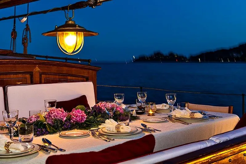 Invader Yacht Photos Pics Elegant dining setup on 1905 Gaff Schooner by G. LAWLEY & Son, USA, at dusk.