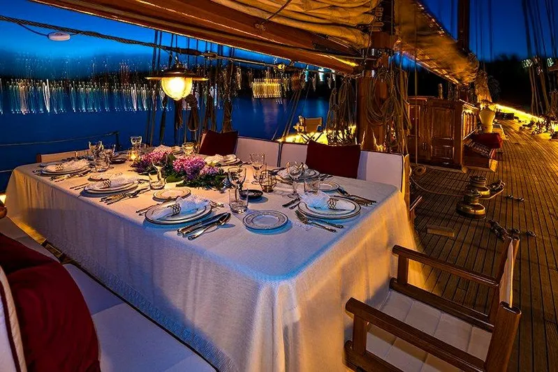 Invader Yacht Photos Pics Luxurious dining setup on 1905 Gaff Schooner by G. LAWLEY & Son, USA, at sunset.