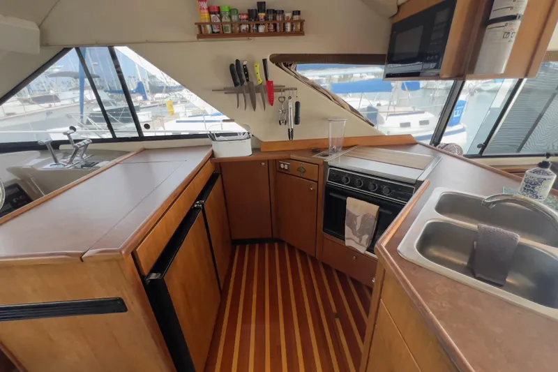  Yacht Photos Pics 1999 Bayliner 3988 Command Bridge Motoryacht kitchen with wooden cabinetry and modern appliances.