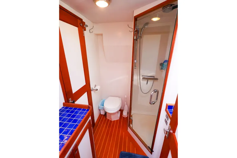  Yacht Photos Pics Luxurious 2005 New England Boatworks Downeast Sedan bathroom with shower and blue-tiled vanity.