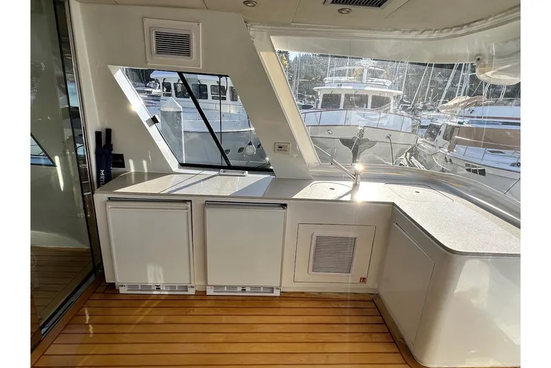 First Home Yacht Photos Pics Luxurious 1988 Cheoy Lee 92 yacht interior with modern kitchenette and wooden flooring.