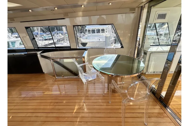 First Home Yacht Photos Pics Luxurious 1988 Cheoy Lee 92 yacht interior with glass table and clear chairs.