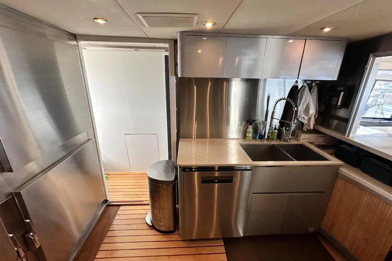 First Home Yacht Photos Pics Modern kitchen interior on 1988 Cheoy Lee 92 yacht, featuring stainless steel appliances and wooden flooring.