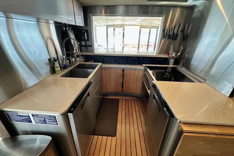 First Home Yacht Photos Pics Modern kitchen interior on 1988 Cheoy Lee 92 yacht, featuring stainless steel appliances and wooden flooring.